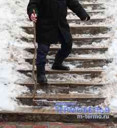 Пожилой мужчина спускается по скользким ледяным ступенькам.